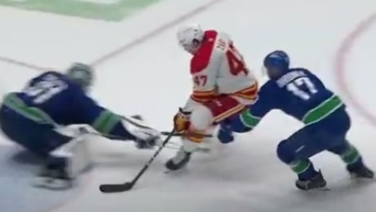 Napastnik Calgary Flames Connor Zary (w białej bluzie) w akcji w meczu z Vancouver Canucks.